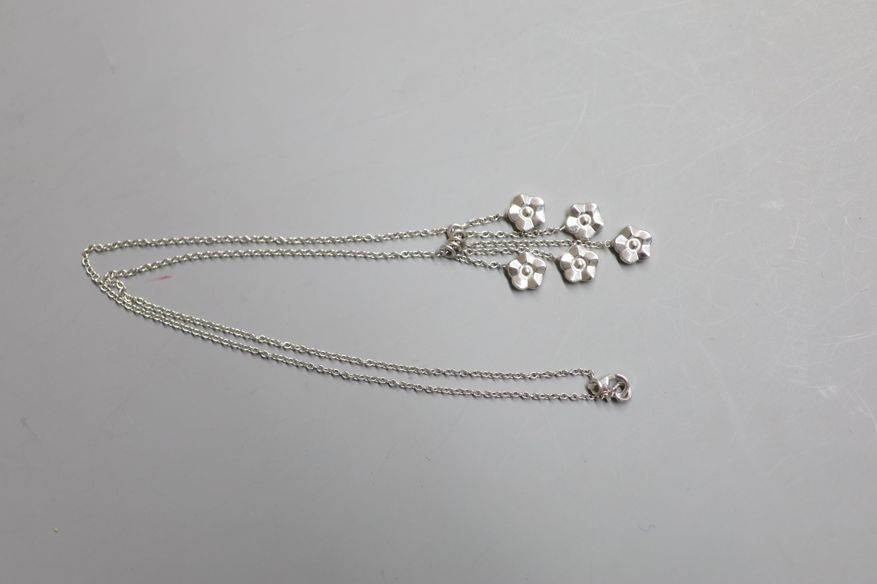 A modern 9ct white gold quintuple flower head cluster drop pendant, 40mm, on a 9ct white gold chain, 41cm, gross 4.9 grams.
